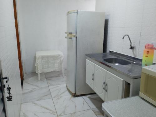 a kitchen with a white refrigerator and a sink at Casinha da Alê in Mongaguá