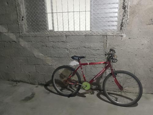 a red bike parked in a room with a window at Casinha da Alê in Mongaguá