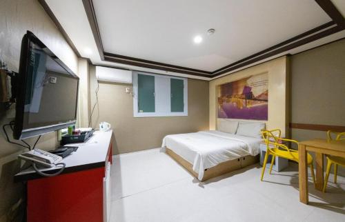 Un dormitorio con una cama y un escritorio con televisión. en City Motel, en Hanam