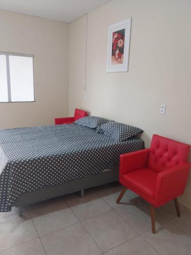 a bedroom with a bed and two red chairs at APT Raphis C in Santarém