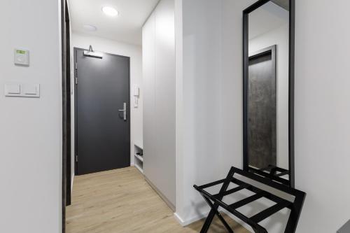 a mirror and a black chair in a hallway at Aparthotel Na Klenici in Mladá Boleslav