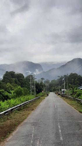 an empty road with mountains in the distance at AA Homestay in Mulu