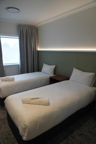 a hotel room with two beds and a window at Tall Timbers Hotel in Ourimbah