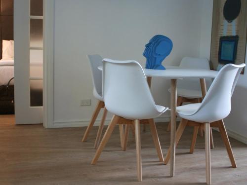 a table and four white chairs in a room at Haven on the Park in Perth