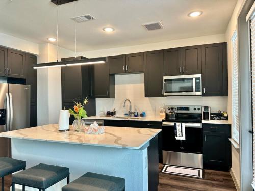 a kitchen with black cabinets and a kitchen island with stools at Cozy apartment near downtown HTX in Houston