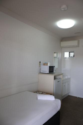 a bedroom with a white bed and a microwave at Park Avenue Hotel Motel in Rockhampton
