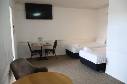 a hotel room with two beds and a table and a tv at Park Avenue Hotel Motel in Rockhampton