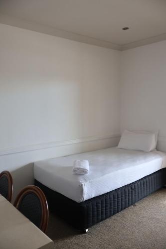 a bed in a room with a white wall at Park Avenue Hotel Motel in Rockhampton