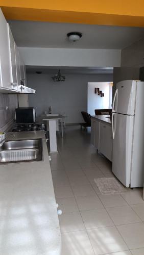 a large kitchen with a refrigerator and a table at Comfortable and perfect location in Lechería in El Morto de Barcelona