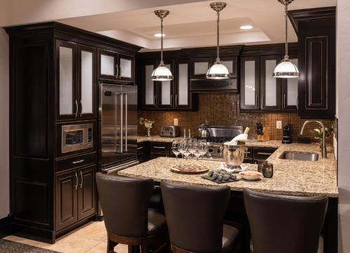a kitchen with black cabinets and a island with bar stools at Waldorf Astoria Park City in Park City