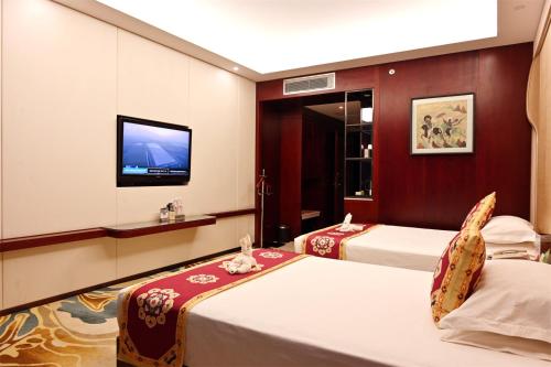 a hotel room with two beds and a flat screen tv at Dunhuang Hotel in Dunhuang
