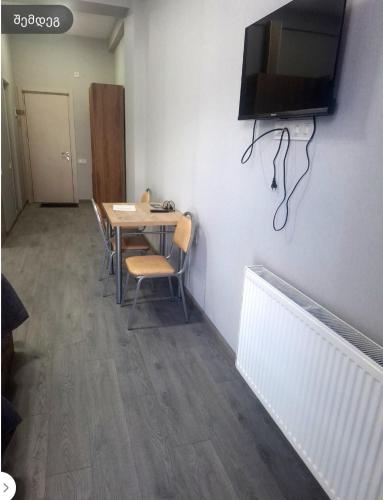 a room with a table with chairs and a television on the wall at ახალი გუდაური საბაგიროსთან in Gudauri
