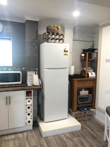 a kitchen with a white refrigerator and a microwave at Water Street - Garden Views in Forster