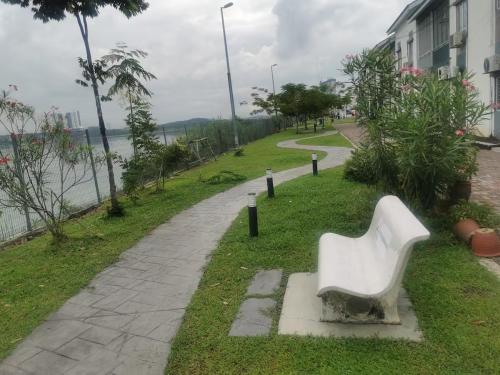 a white bench sitting on the grass next to a sidewalk at Lake Residence No165 @aesthetic lake view & best photograph in Puchong