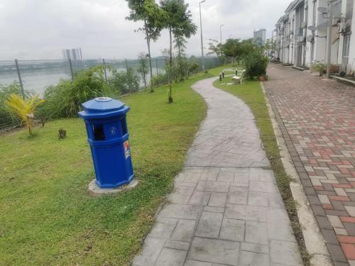 a blue trash can sitting on the grass next to a sidewalk at Lake Residence No165 @aesthetic lake view & best photograph in Puchong