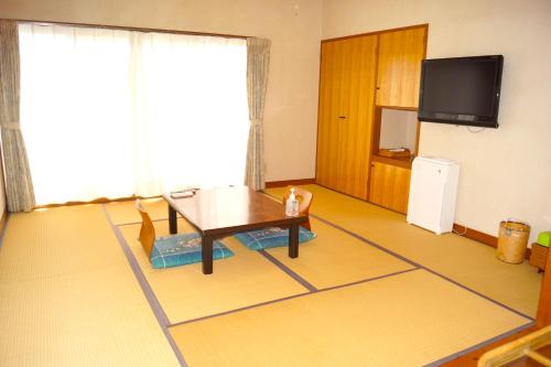 a living room with a table and a tv at タートルハウス in Shimoda
