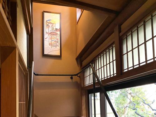 a hallway with windows and a painting on the wall at Muromachi Yutone Kyokoyado in Kyoto