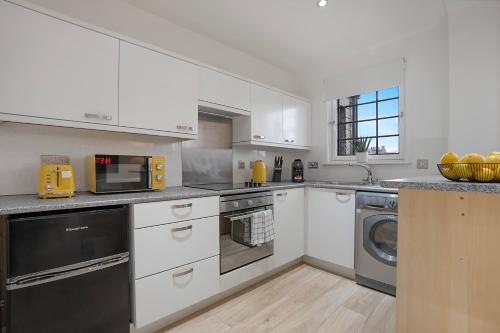 a kitchen with white cabinets and a washer and dryer at George Street Apartment - Grampian Lettings in Aberdeen