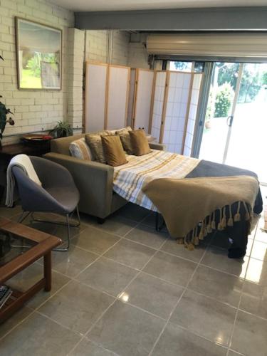 a bedroom with a bed and a couch and a chair at Water Street - Garden Views in Forster