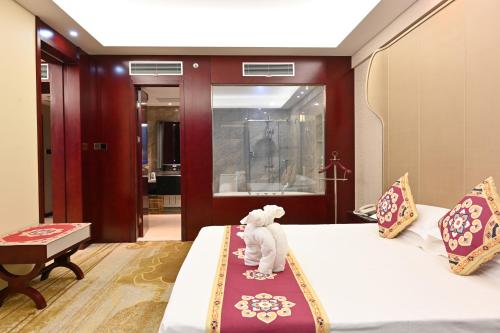 a white cat sitting on a bed in a room at Dunhuang Hotel in Dunhuang