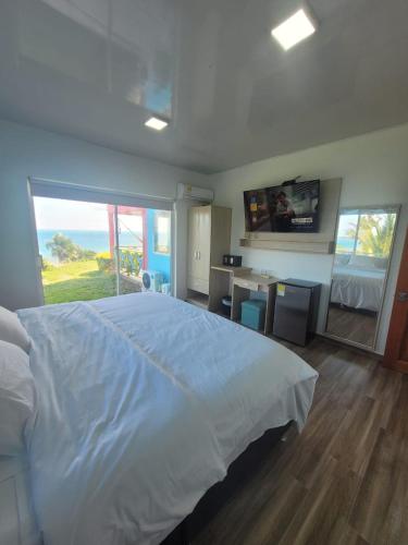 a bedroom with a large white bed and a television at 321 Surprise Beach house and Glamping in Providencia