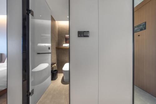 a bathroom with a toilet and a white door at Atour Hotel Wefang High Tech Zone Management Committee East Jiankang Street in Weifang