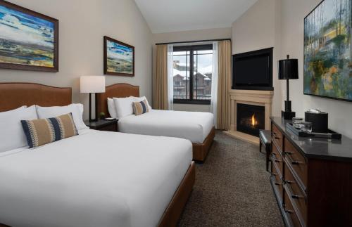 a hotel room with two beds and a fireplace at Waldorf Astoria Park City in Park City