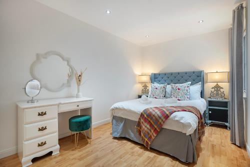 a bedroom with a bed and a dresser and a mirror at George Street Apartment - Grampian Lettings in Aberdeen