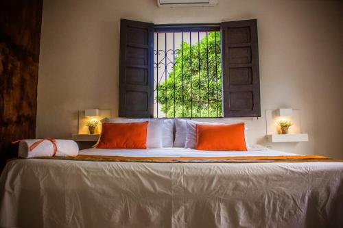 a bed with two orange pillows and a window at Capilla del sol in Garzón