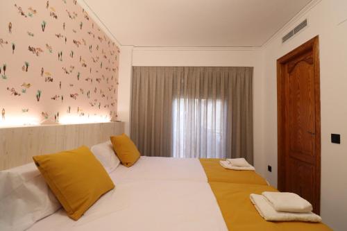 a bedroom with a large white bed with yellow pillows at Hotel Posada del Mar Playa de Gandía in Puerto de Gandía