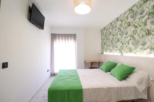 a bedroom with a bed with two green pillows at Hotel Posada del Mar Playa de Gandía in Puerto de Gandía