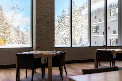 a dining room with tables and chairs and windows at Okujozankei Onsen Kasho Gyoen in Jozankei