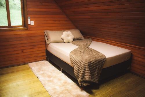 a small bed in a cabin with a teddy bear on it at Chalé Recanto do Vale pomerode in Pomerode