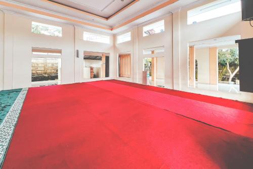 a red carpet in a large room with windows at RedDoorz Premium at Hotel Riyadi Syariah in Gunungcupu