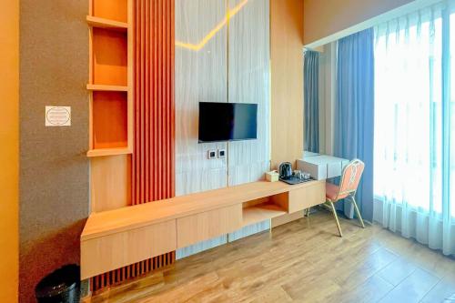 a room with a desk with a tv on a wall at RedDoorz Premium at Hotel Riyadi Syariah in Gunungcupu