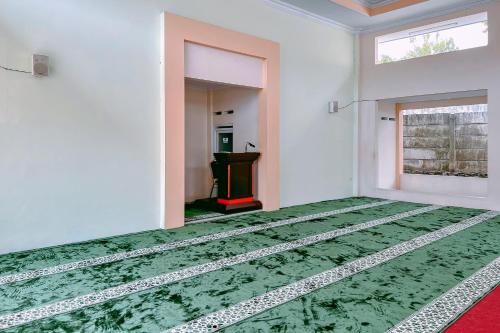 a room with a green rug on the floor at RedDoorz Premium at Hotel Riyadi Syariah in Gunungcupu