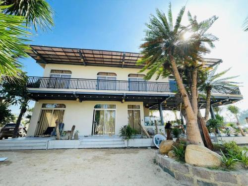 une maison avec un palmier devant dans l'établissement Hòn Đỏ Homestay Ninh Thuan Venuestay, à Mỹ Thanh