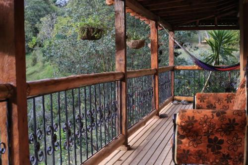 a porch with a hammock and a chair on a balcony at Luna Verde Eco Hábitat in Rionegro