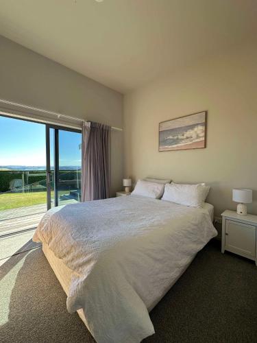 Un dormitorio con una cama grande y una ventana grande. en Coastal Paradise, en Raglan