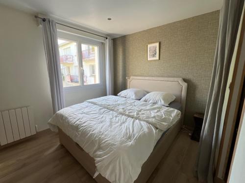 une chambre avec un lit avec des draps blancs et une fenêtre dans l'établissement Charmant 2P en Hyper Centre de Lorient - Lumineux avec Balcon - 2/3 Couchages. - FR-1-349-221, à Lorient