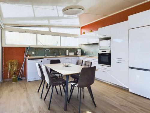 une cuisine avec des armoires blanches et une table et des chaises dans l'établissement Villa 3 chambres climatisée près de la plage avec parking privé à Marseillan-Plage - FR-1-326-845, à Marseillan