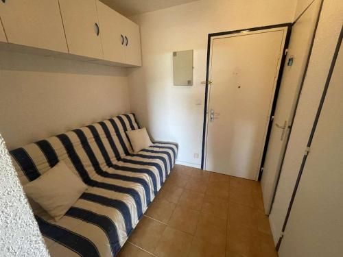 - un canapé rayé dans une petite chambre avec une porte dans l'établissement Studio Cabine avec Vue Piscine, Parking Privé - FR-1-328-274, à La Grande Motte