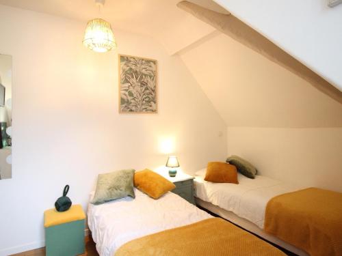 Cette chambre mansardée comprend 2 lits et un lustre. dans l'établissement Spacieux T3 La Bourboule, 2 chambres, proche thermes - FR-1-608-284, à La Bourboule