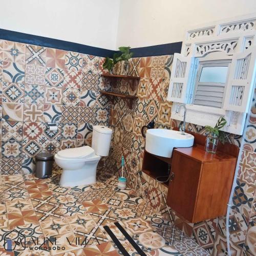 a bathroom with two toilets and a sink and tiles at Aline Villa in Wonosobo