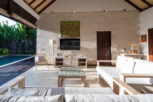 a living room with a couch and a tv at Villa Nolan - Modern 3BR Private Villa with Pool in Padonan, Canggu in Kerobokan