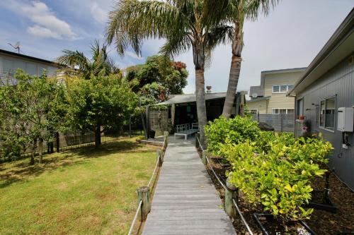 a walkway in a yard with palm trees and a house at Aquila Nest in Whitianga