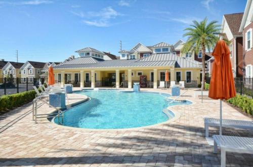 a swimming pool with umbrellas in front of a house at Disney here we go in Orlando