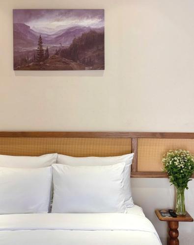 a bed with white pillows and a painting on the wall at Túi Ba Gang Boutique Hotel in Da Lat