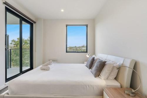 a white bedroom with a large bed and a window at Cozy & Convenient Bundoora Apt withparking in Bundoora