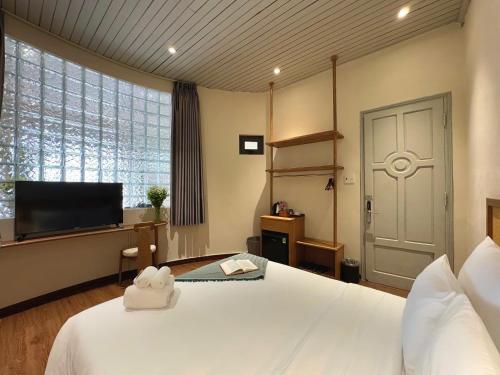 a bedroom with a large white bed and a flat screen tv at Túi Ba Gang Boutique Hotel in Da Lat